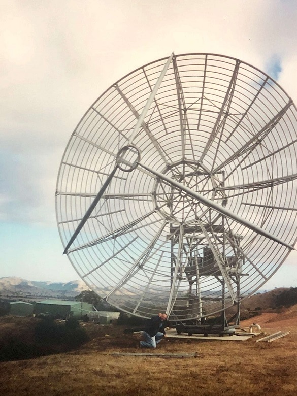 A man works on a large antenna in a paddock in Birchip, Victoria