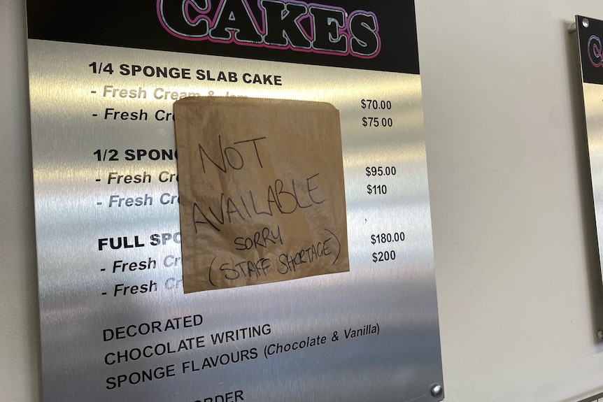A cake board sign with a 'not available, sorry, short staff' sign on it. 