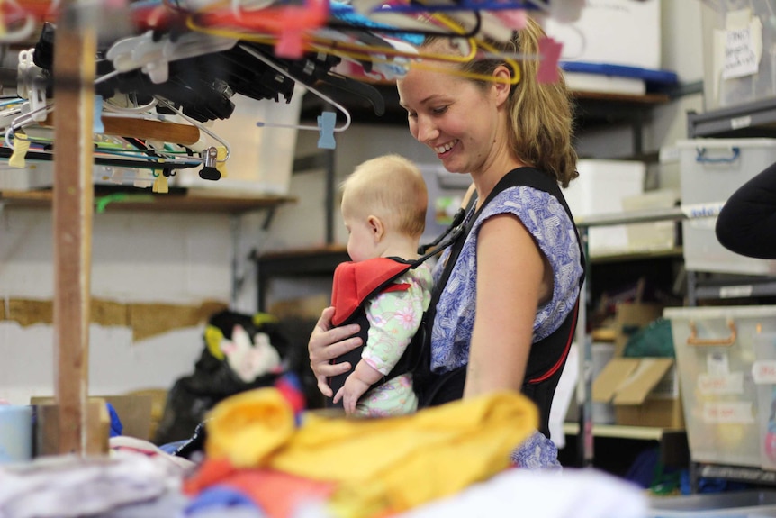 A woman and a baby with second hand clothing.