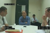 Robert Xie sits in a police interview room with three investigators