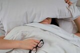 Young woman in bed with pillow over her face