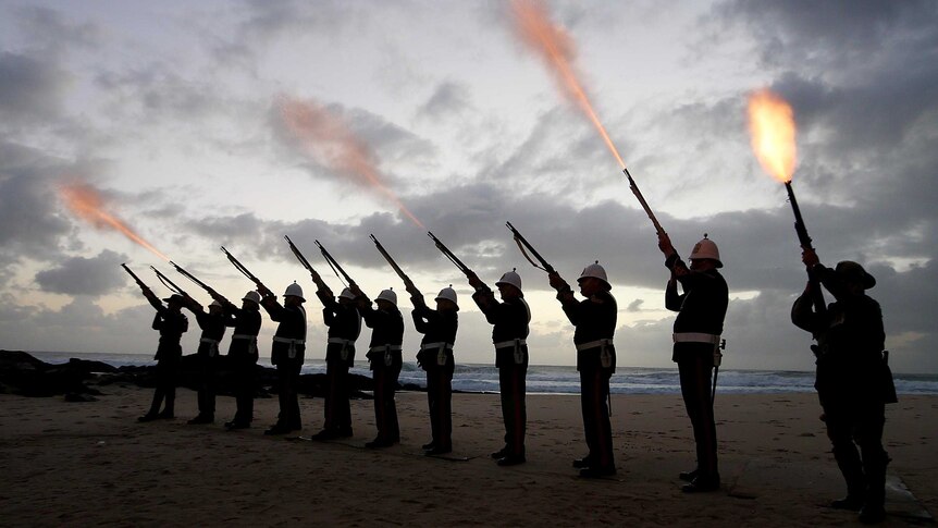 Silhouetted members of the Albert Battery shoot a volley of fire into the air on the beach at Currumbin.