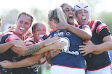 Sydney Roosters players gather and smile in celebration