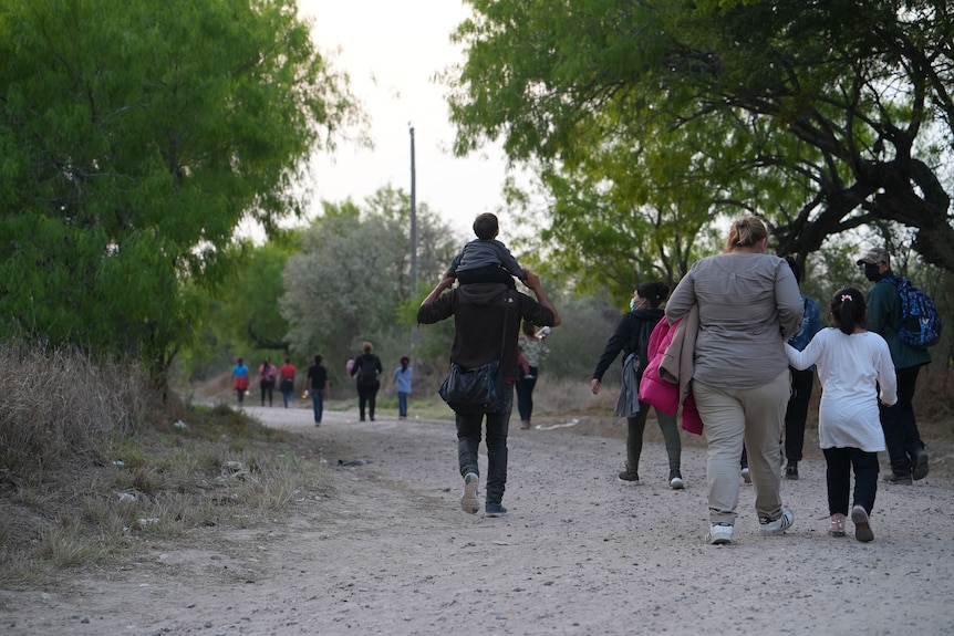 A group of people walk along a sandy path.