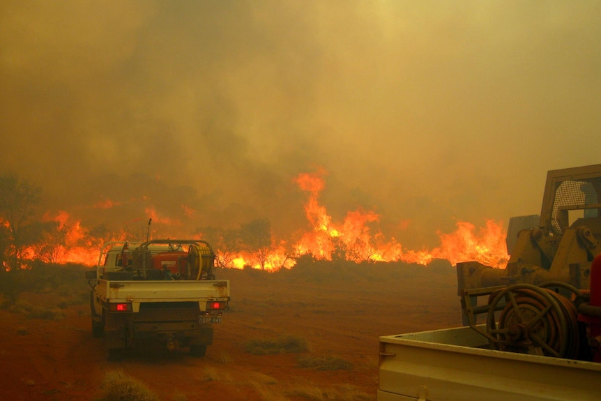 Fire fighting vehicles approach bushfires burning in the Kennedy Range National Park in WA.