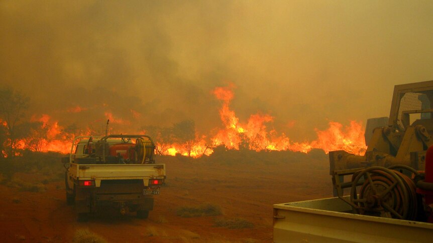 Fire fighting vehicles approach bushfires burning in the Kennedy Range National Park in WA.