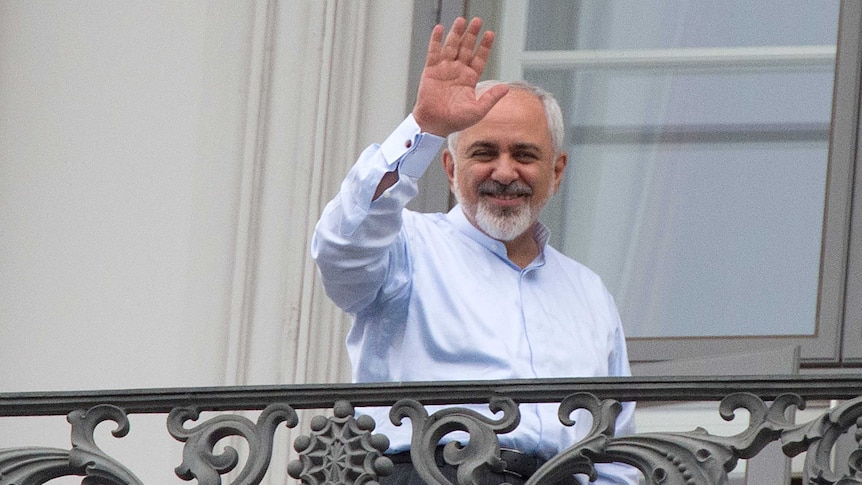 Iranian foreign minister Mohammad Javad Zarif waves from a balcony of the Palais Coburg Hotel.