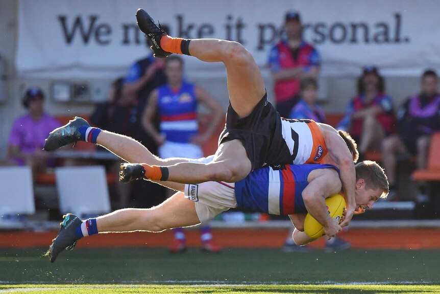 Lachie Hunter is in the air, horizontal with the ground holding the ball. Daniel Lloyd is on top of him, legs flailing.