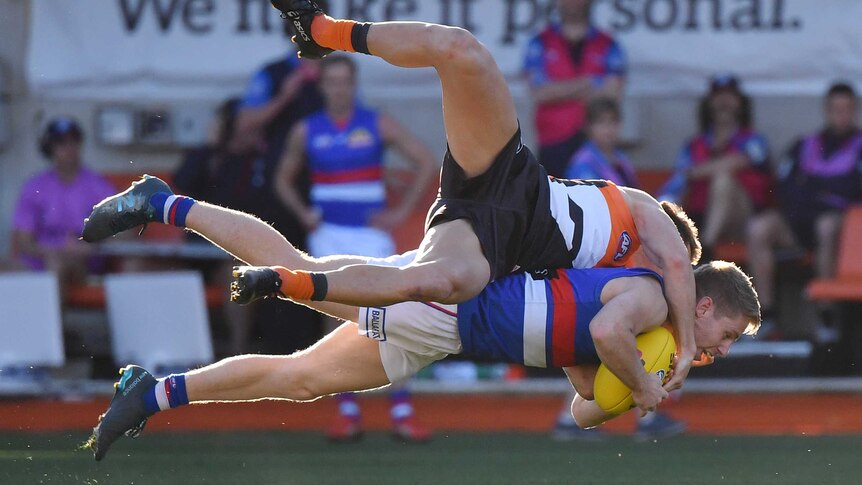 Lachie Hunter is in the air, horizontal with the ground holding the ball. Daniel Lloyd is on top of him, legs flailing.