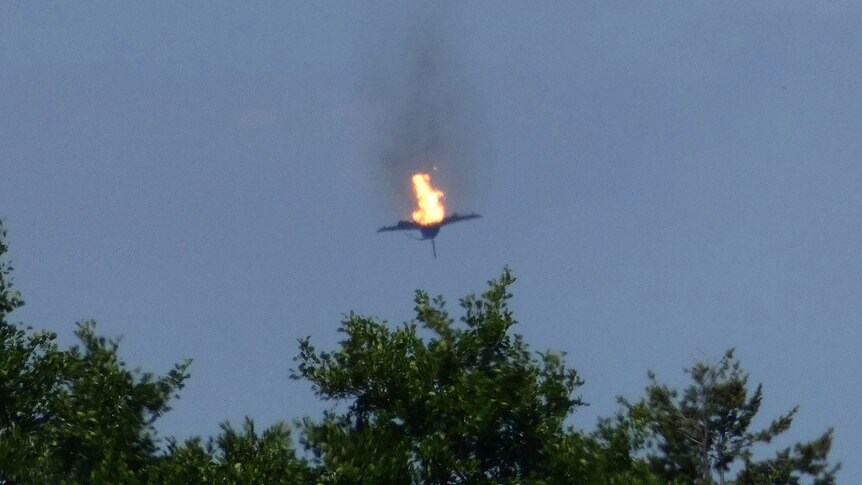 A burning jet falls from a clear sky.
