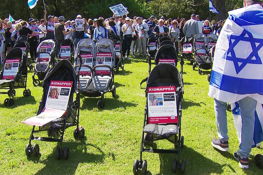 Prams sitting in a park with posters about hostages sitting in them.
