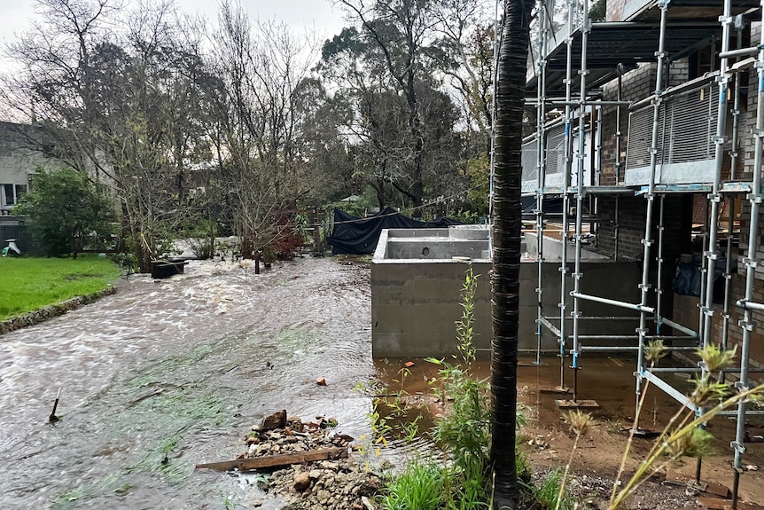 Creekbed and road overflowing with water outside a house