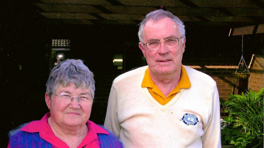 A middle-aged man and woman standing in a courtyard garden.