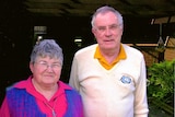 A middle-aged man and woman standing in a courtyard garden.