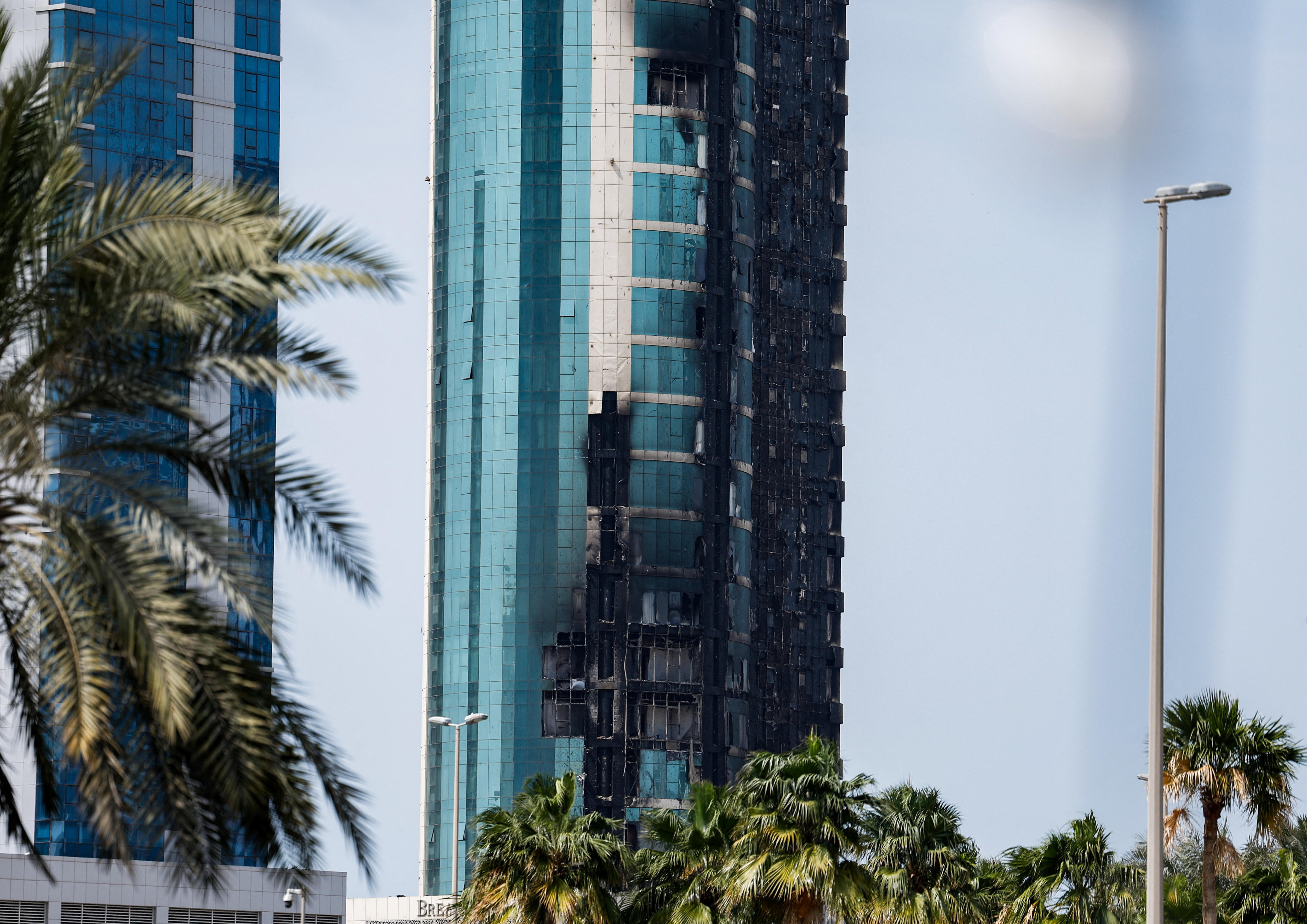 The side of a building with glass windows broken and burned