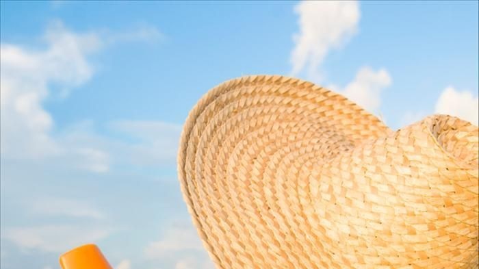 Woman wearing hat and applying sunscreen
