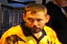 A man in a yellow fishing shirt sitting at the bar of a pub. 