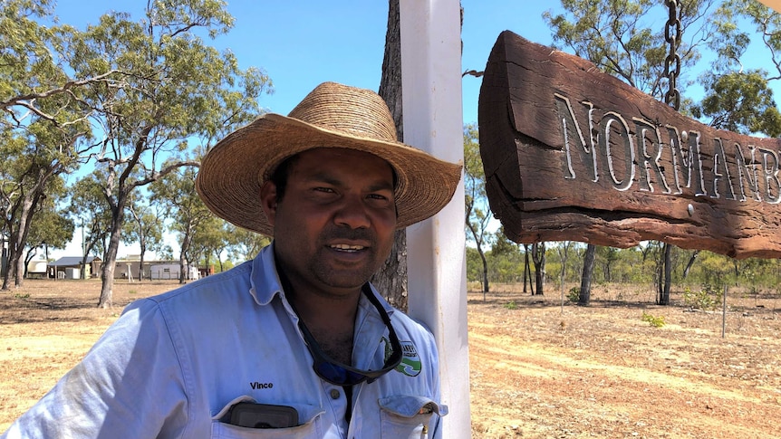 An indigenous cattleman leans on a signpost at the entrance of a cattle property near Cooktown