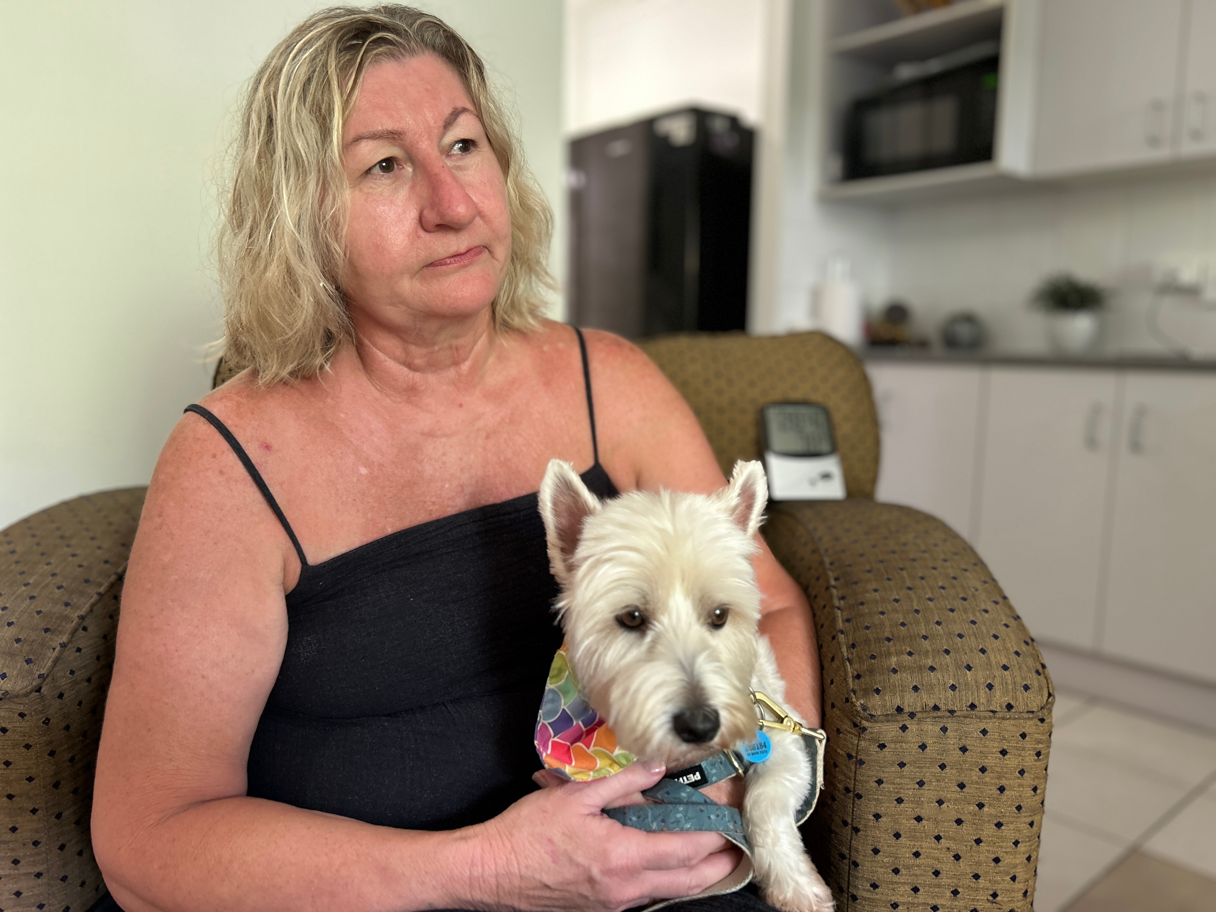 Woman in black singlet on couch with white dog