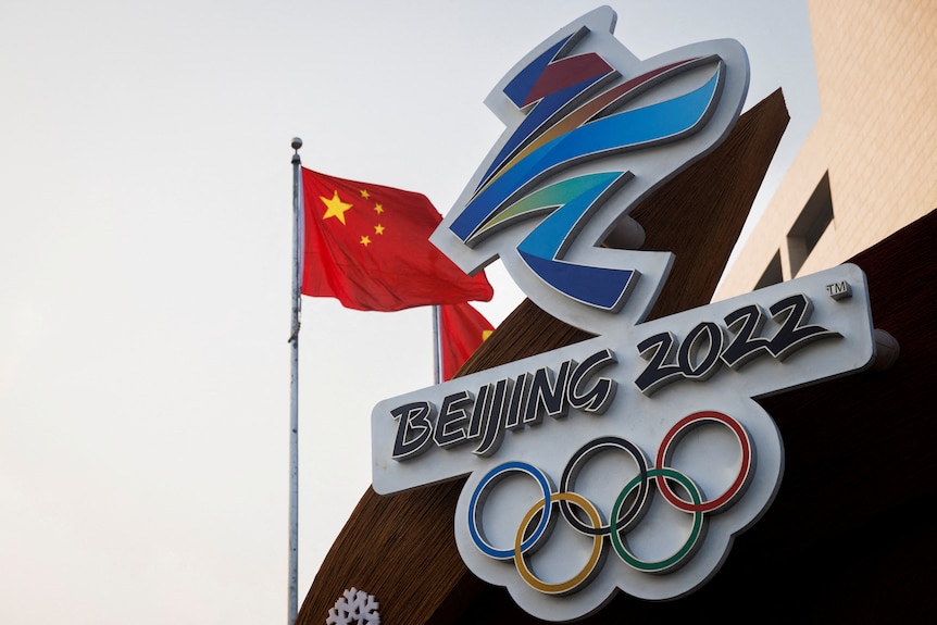 The Chinese national flag flies behind the logo of the Beijing 2022 Winter Olympics.