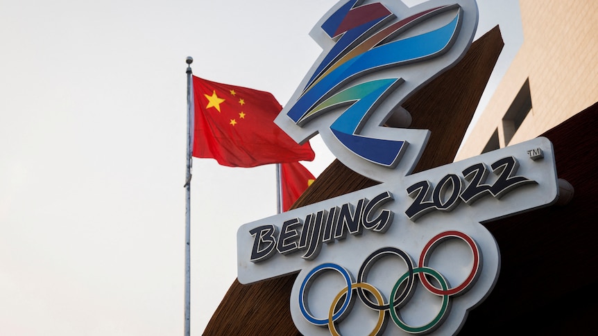 The Chinese national flag flies behind the logo of the Beijing 2022 Winter Olympics.