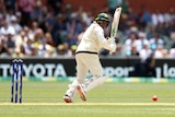 An Australian batsman looks over his shoulder to watch the ball after playing a delivery off his pads in a Test match.