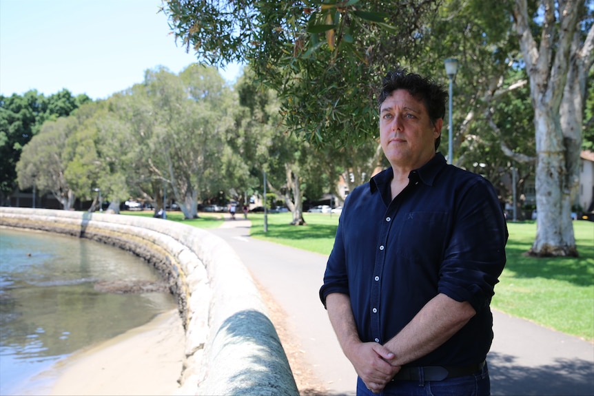 Man stands in park in a black shirt
