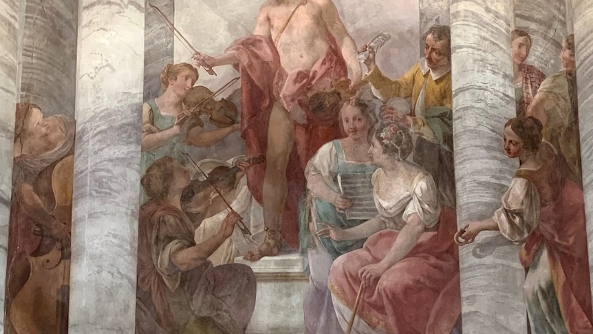 A faded fresco depicting a small concerto group, with one woman clutching a stylized page of sheet music 