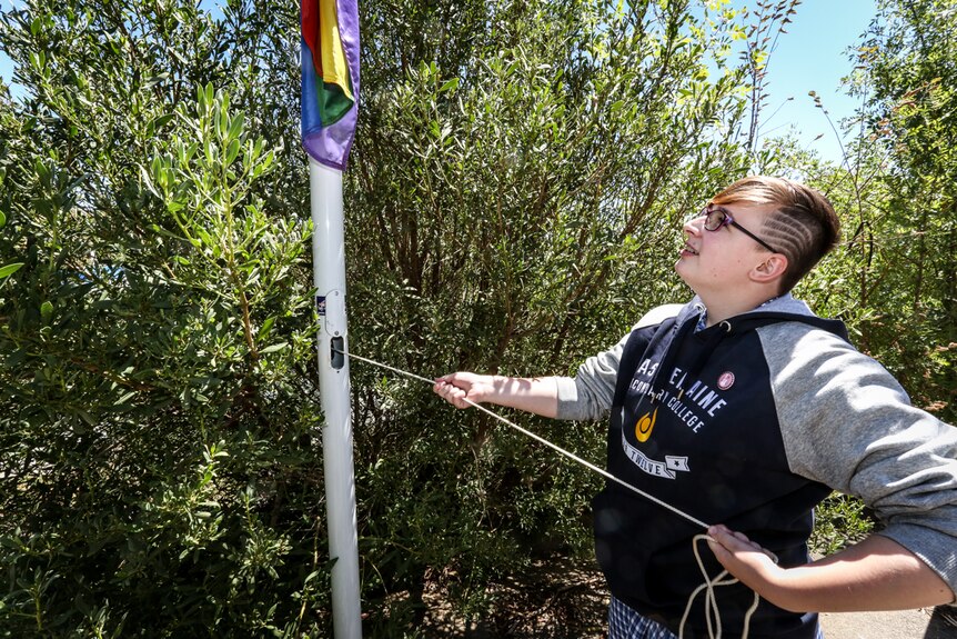 Year 12 student Olivia Hocking raising the Rainbow flag.