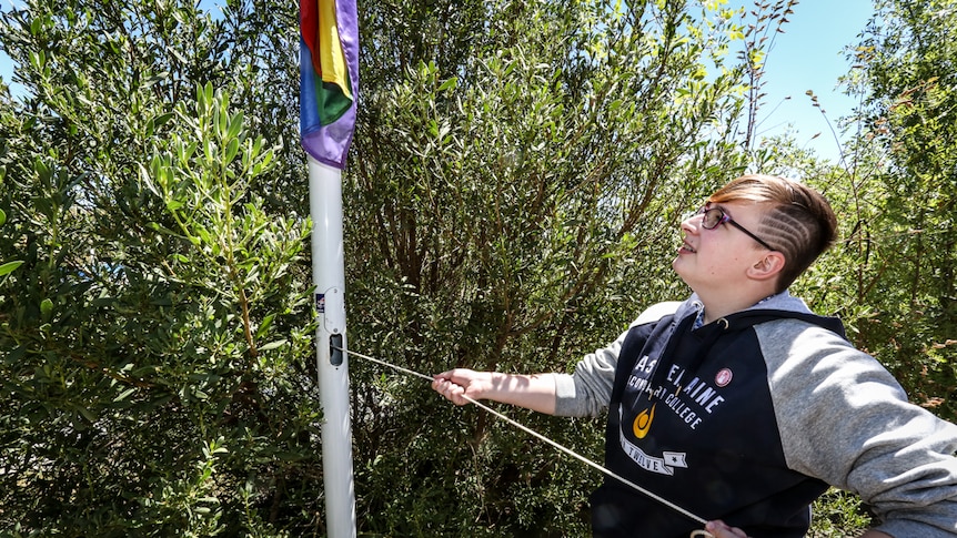 Year 12 student Olivia Hocking raising the Rainbow flag.