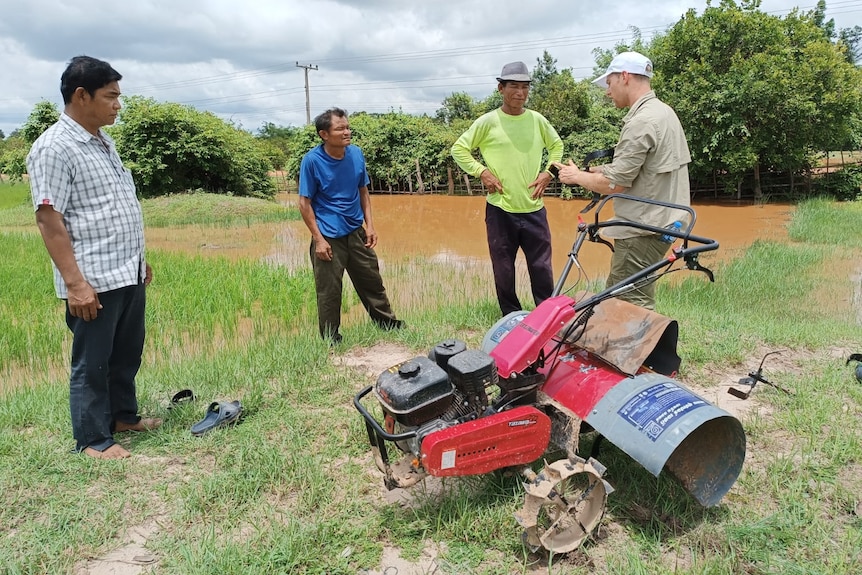 Matt Champness standing with Laotian rice growers