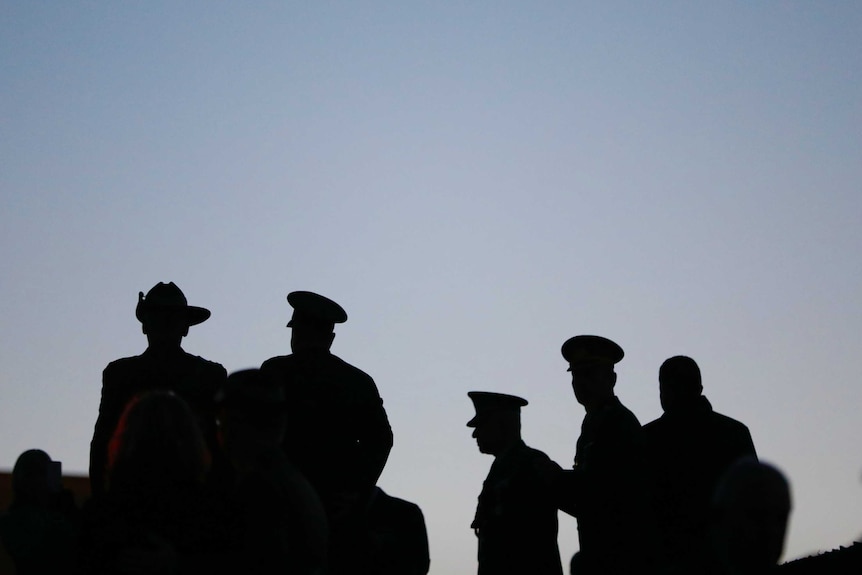 Silhouettes of military personnel at the national Anzac Day dawn service