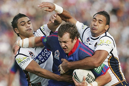 Clint Newton is tackled by Broncos Karmichael Hunt and Justin Hodges