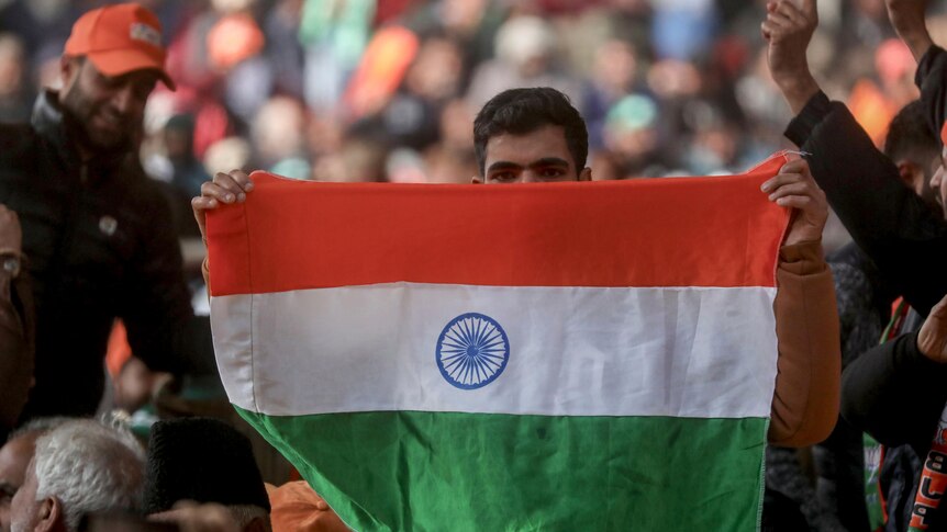 Man holding up Indian flag at a rally.