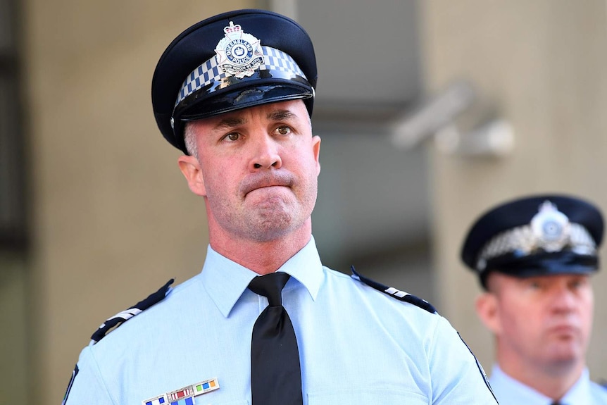 A uniformed policeman looks pensive as he speaks to reporters