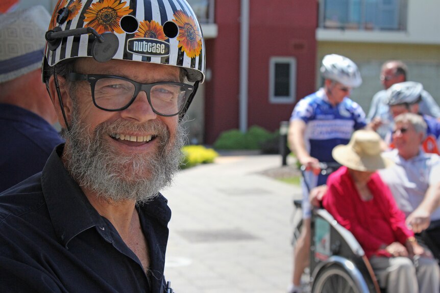 Man with a beard wearing a flower helmet.
