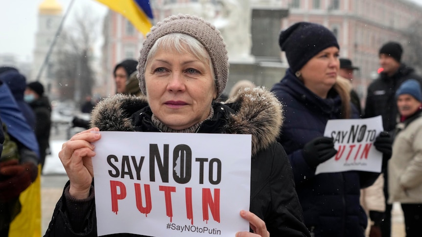 An activist in Kyiv holds up a sign saying "say no to Putin".