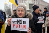 An activist in Kyiv holds up a sign saying "say no to Putin".