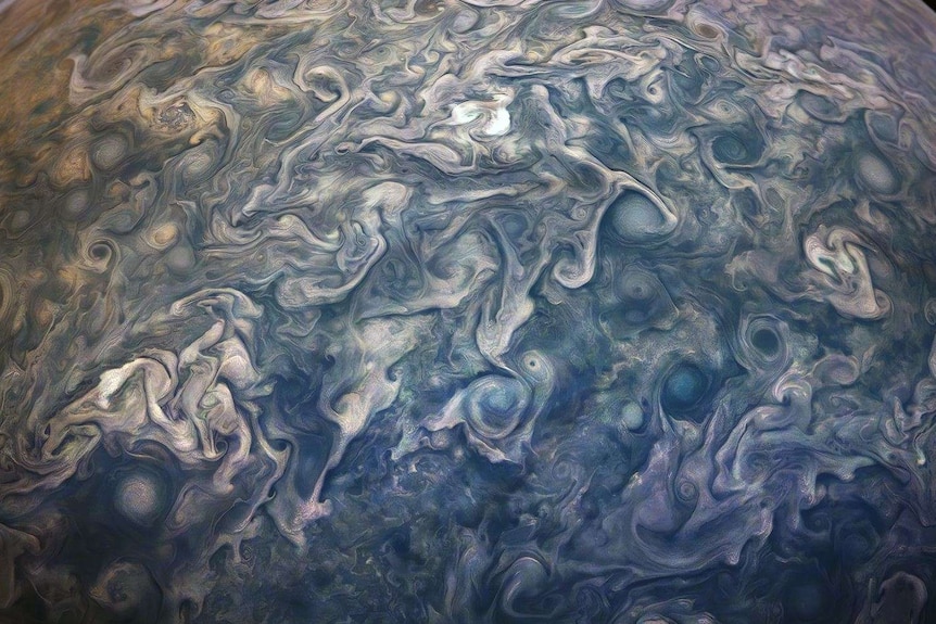 A series of blues, greens and purples swirl over a spherical surface.