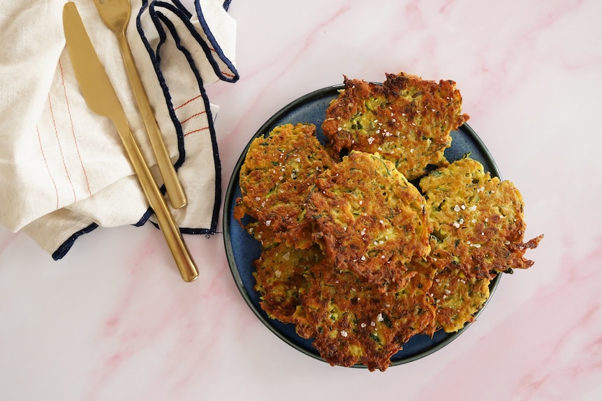 A plate of zucchini fritters sprinkled with sea salt, an easy way to use excess zucchini and fill lunchboxes.