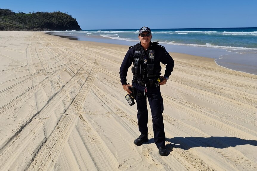 A policeman standing on a beach.