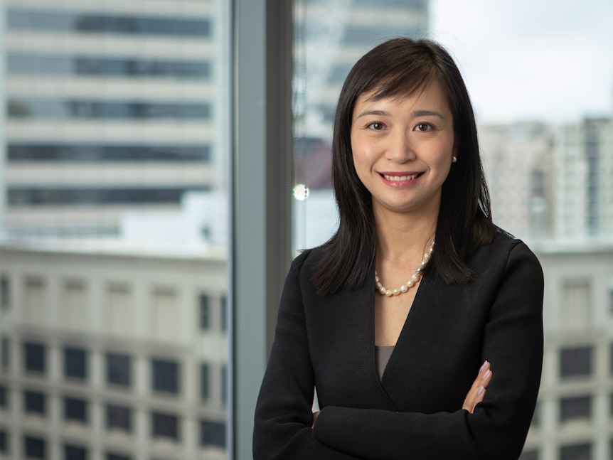 Woman smiling to camera with her arms folded against a skyscraper background