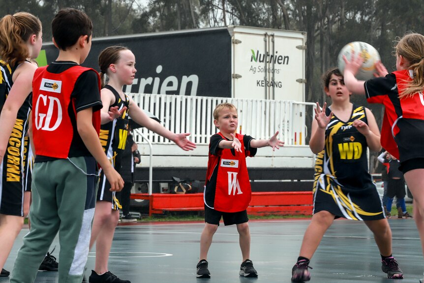 Children playing netball on an outside court wearing bright coloured uniforms