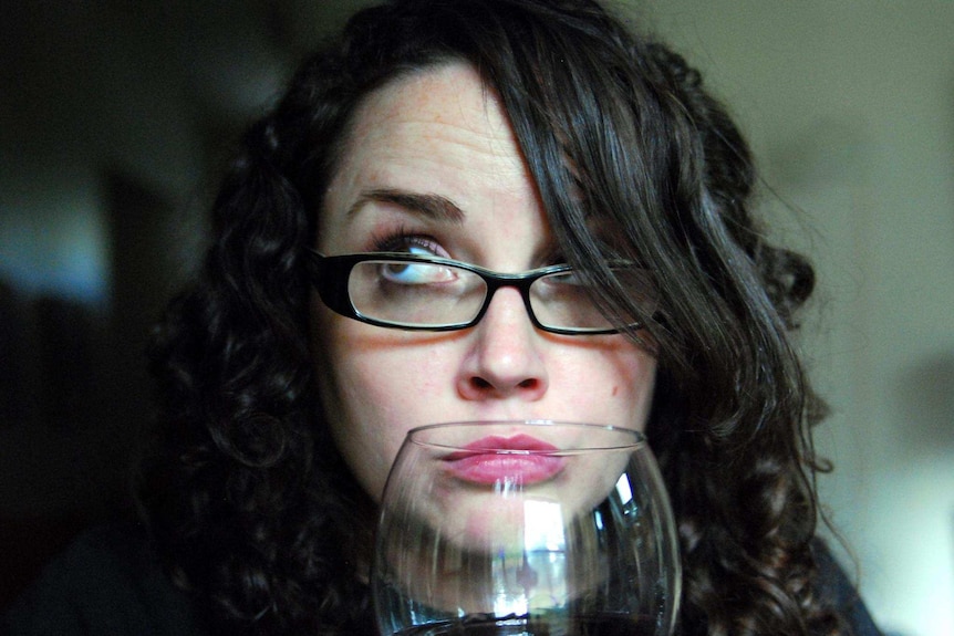 A woman smelling a glass of red wine.