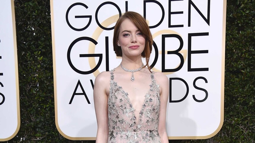Emma Stone wears a pastel pink floor length gown with silver details