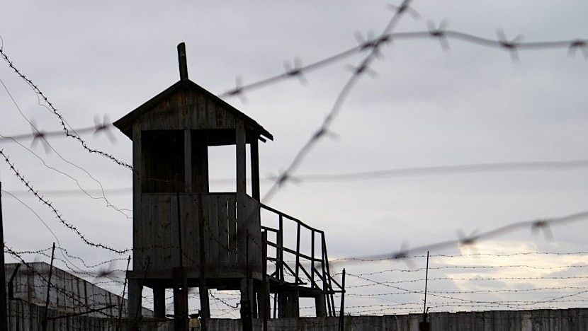 A wooden watch tower surrounded by razor wire keeps watch over the now empty prison yard.