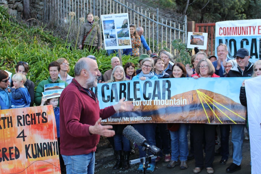 Ted Cutlan speaks to a small crowd with banners.