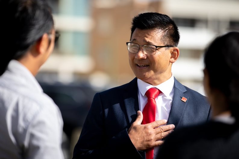 MId shot of Sam Lim wearing glasses and suit with red tie