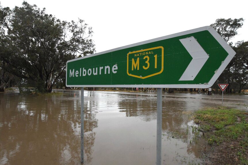 Floodwaters approach a about 50cm highk on a road sign indicating Melbourne