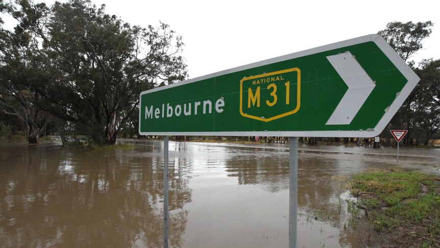 Floodwaters approach a about 50cm highk on a road sign indicating Melbourne